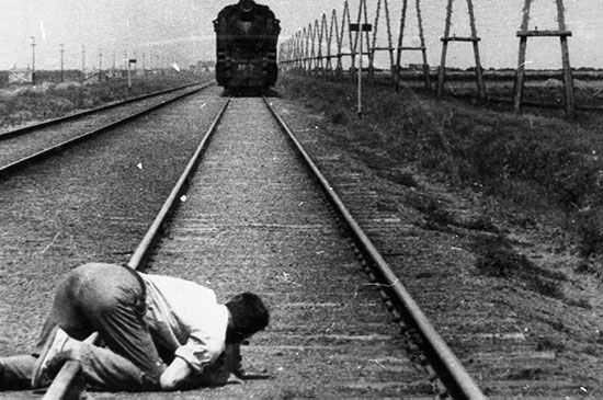 Dziga Vertov se arrodilla para filamr un tren en la pelicula Hombre con una cámara, (1929).